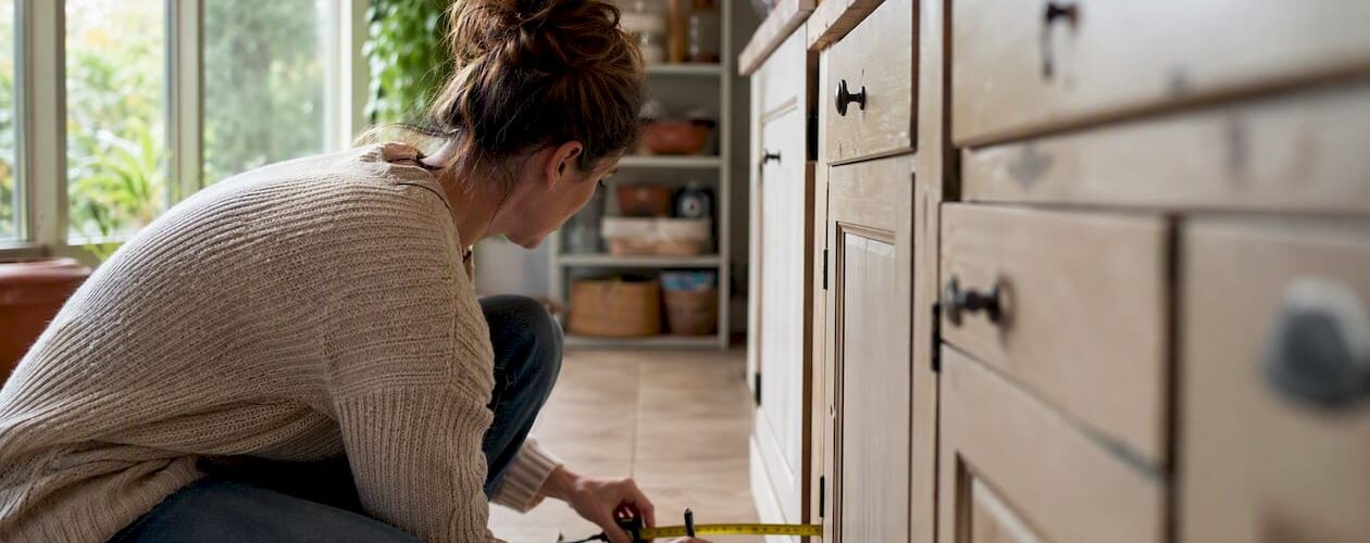 Hands measuring kitchen cabinet