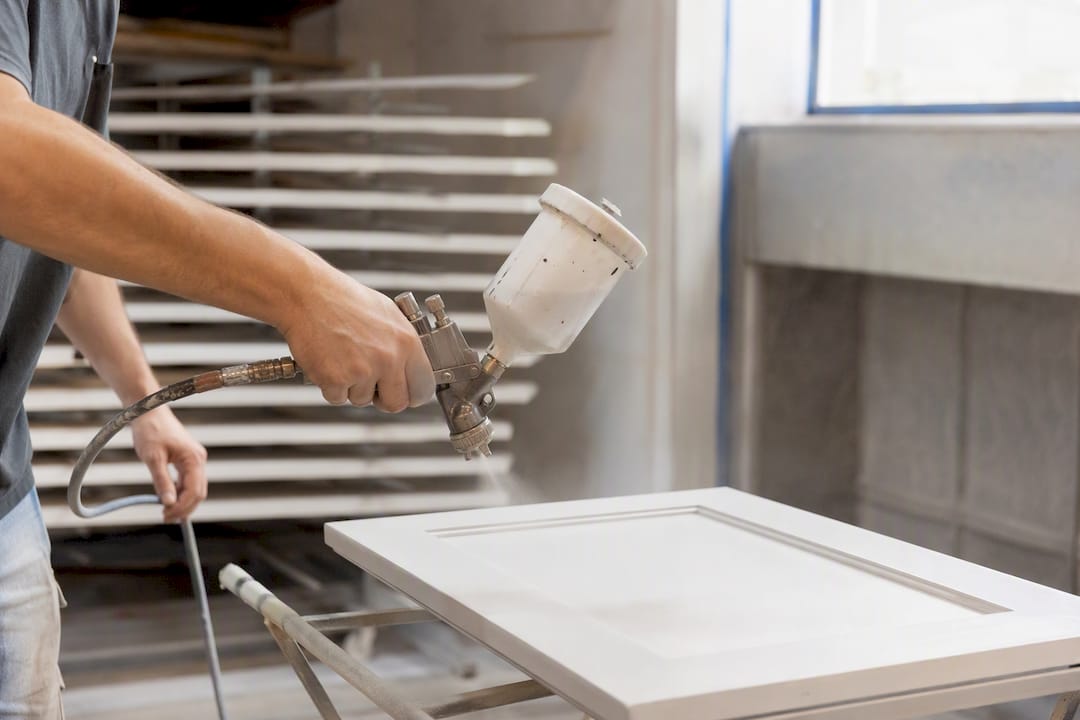 Technician hand spraying cabinet door finish
