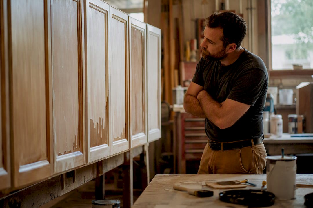 Refinisher inspecting cabinets with paint drips