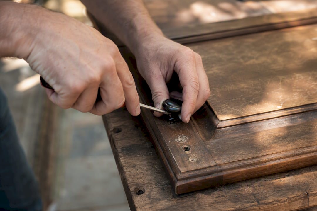 Hands removing cabinet knob from door